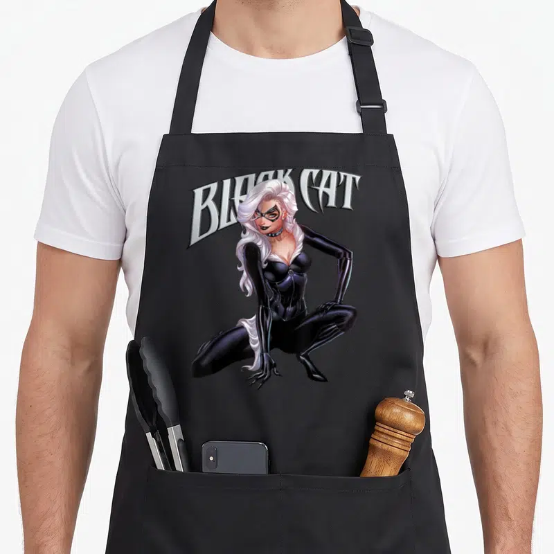 Felicia black cat apron - Crouching character in black suit with arched BLACK CAT text in realistic style — shown on a black cotton canvas apron against a white background