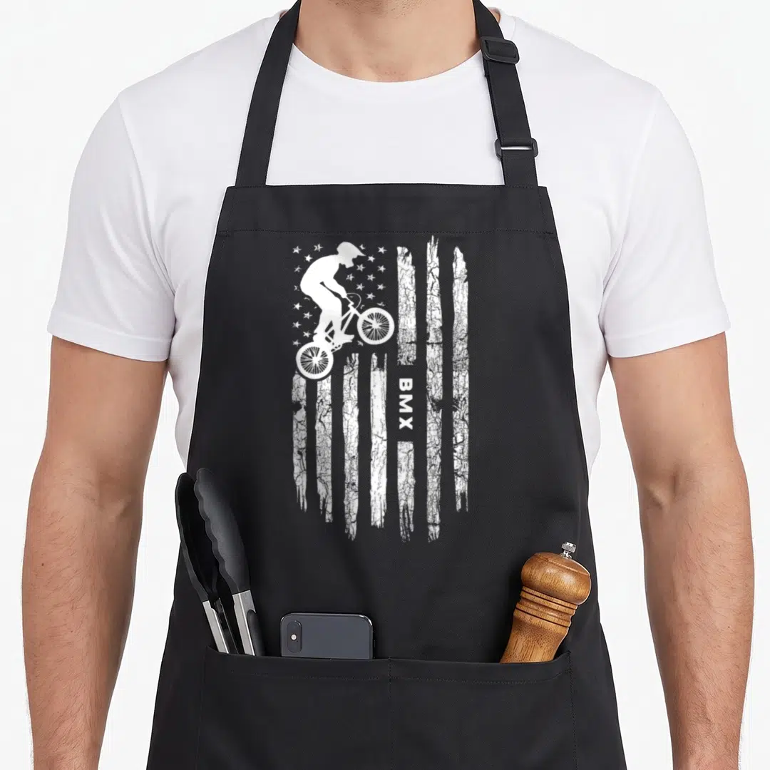 Bmx american flag apron - White BMX rider silhouette with stars and vertical distressed stripes containing vertical BMX — shown on a black cotton canvas apron against a white background