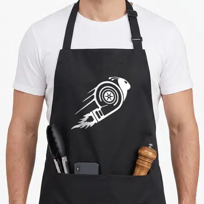 Turbo racing apron - White snail silhouette shaped like a rocket with speed lines and fire trails on black background — shown on a black cotton canvas apron against a white background