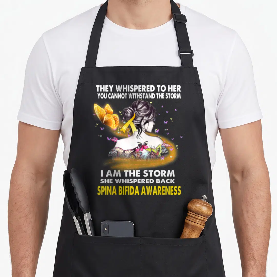 Storm spina bifida awareness apron - Woman with yellow ribbon and butterflies flanked by storm awareness text in white — shown on a black cotton canvas apron against a white background