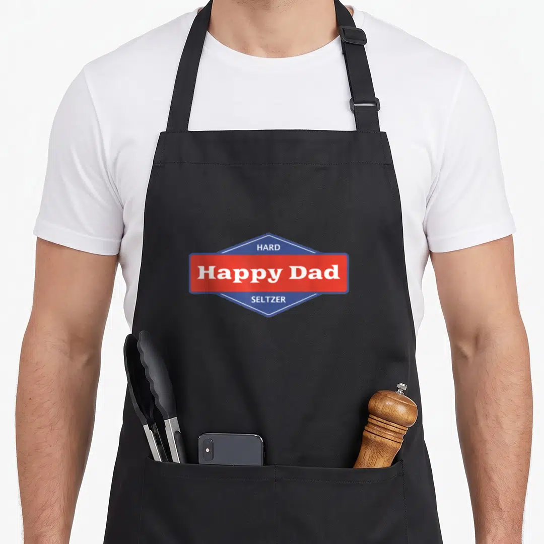 Hard father day apron - Blue hexagon logo with red rectangle containing Happy Dad Hard Seltzer text in white — shown on a black cotton canvas apron against a white background