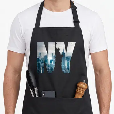Statue new york apron - NY letters filled with blue and white NYC skyline photo showing Statue of Liberty and Empire — shown on a black cotton canvas apron against a white background