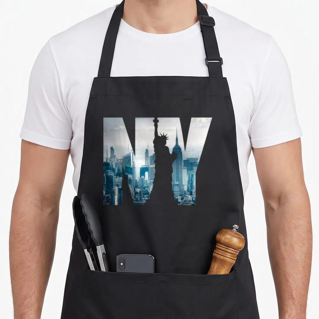 Statue new york apron - NY letters filled with blue and white NYC skyline photo showing Statue of Liberty and Empire — shown on a black cotton canvas apron against a white background