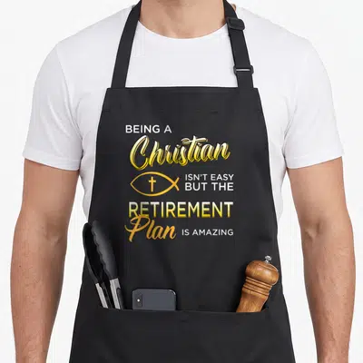 Gospel christian apron - Stacked yellow and white text reading BEING A Christian ISN'T EASY BUT THE RETIREMENT Plan IS — shown on a black cotton canvas apron against a white background