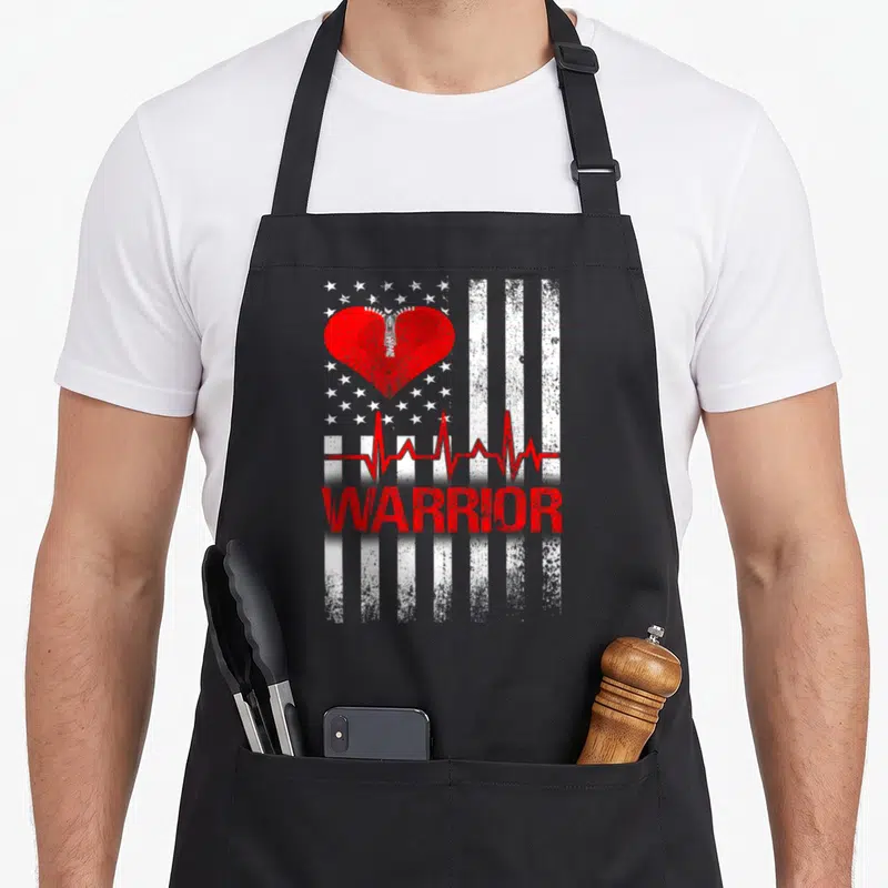 Patient open apron - Red zippered heart and WARRIOR text on white striped background — shown on a black cotton canvas apron against a white background
