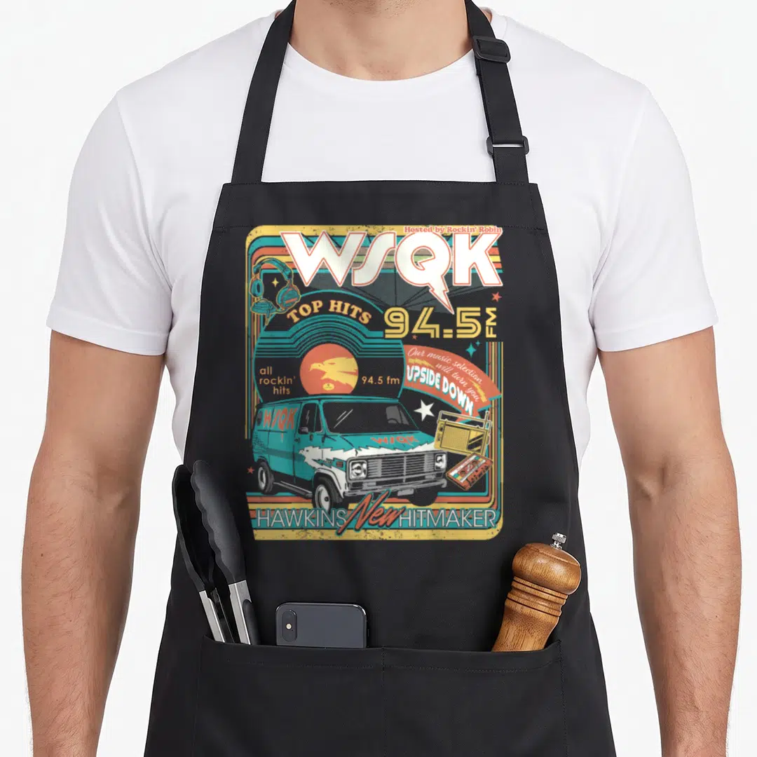 Wsqk stranger apron - Retro WSQK radio station graphic with teal van and Upside Down text in blue yellow red white — shown on a black cotton canvas apron against a white background