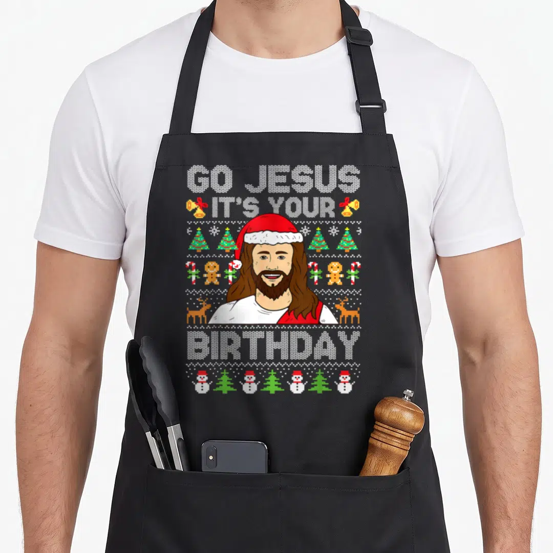 Jesus ugly christmas sweater apron - Go Jesus It's Your Birthday text with Jesus portrait and rows of Christmas icons — shown on a black cotton canvas apron against a white background