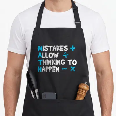 Funny math teacher apron - Mistakes Allow Thinking to Happen text with blue plus percent minus x symbols — shown on a black cotton canvas apron against a white background