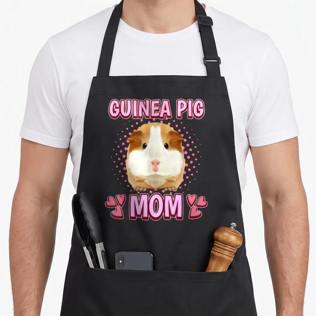 Guinea pig mother's day aprons - Cartoon brown and white guinea pig over pink dots with GUINEA PIG MOM text and four — shown on a black cotton canvas apron against a white background