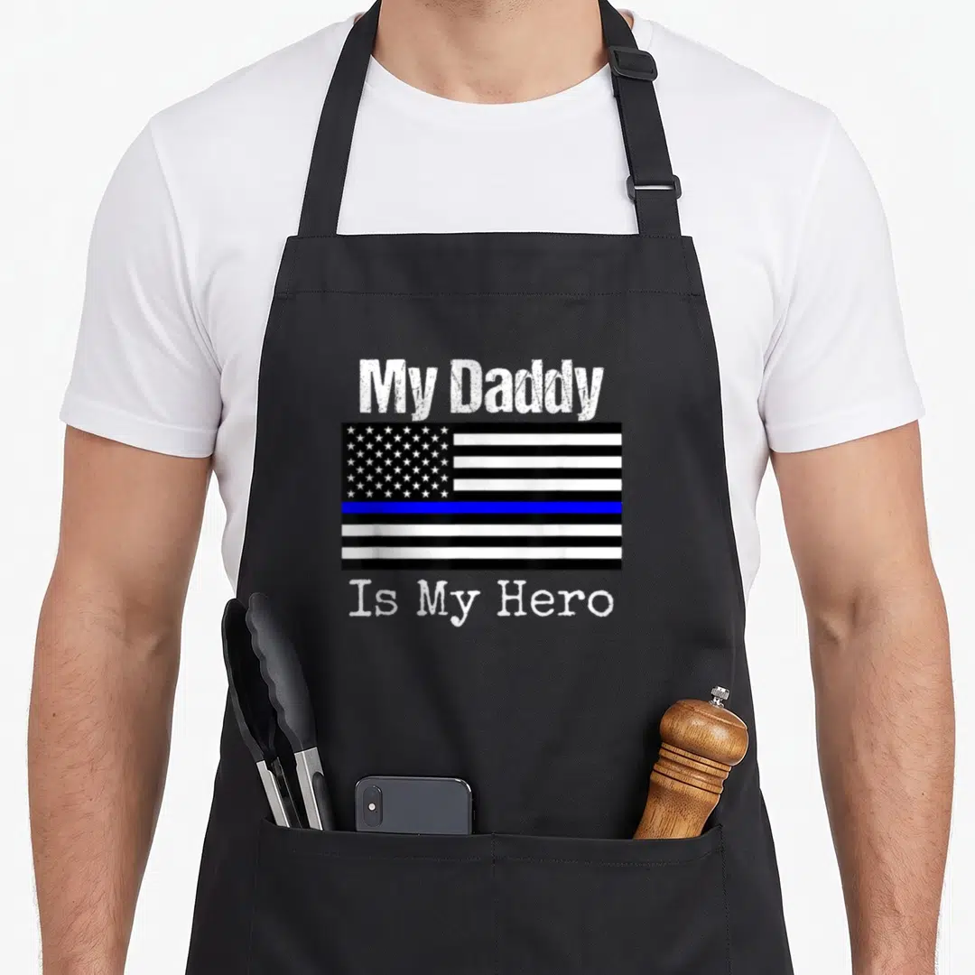 Daddy police apron - Distressed My Daddy Is My Hero text flanking a black white and blue line flag — shown on a black cotton canvas apron against a white background