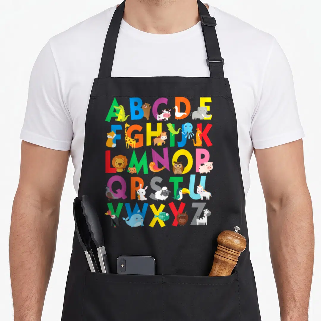 Learning animal apron - Colorful A-Z alphabet grid with cartoon animals standing next to letters — shown on a black cotton canvas apron against a white background