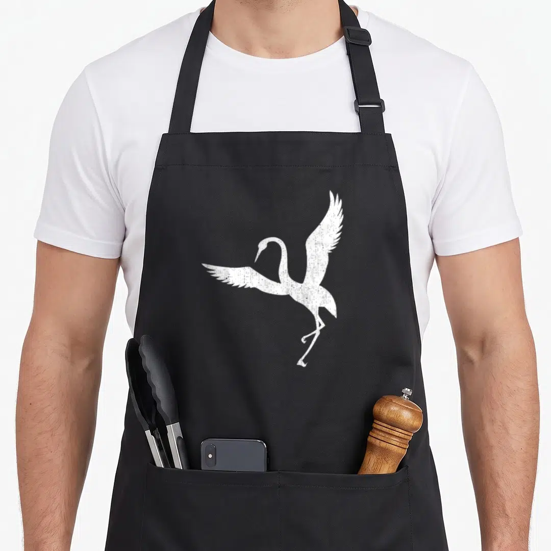 Sandhill sparrow dad apron - White distressed crane silhouette with spread wings and trailing legs on grey background — shown on a black cotton canvas apron against a white background