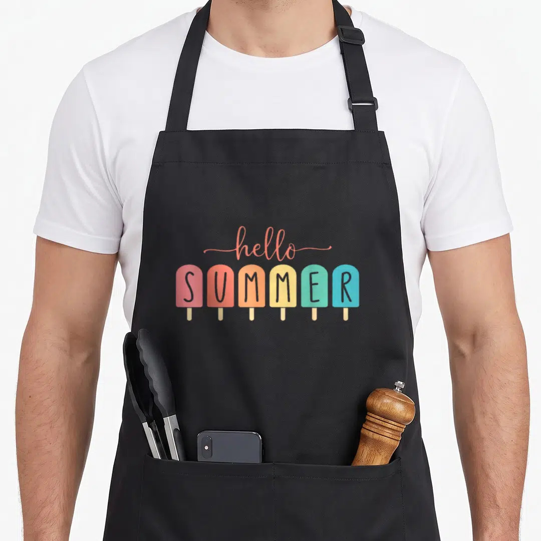 Hello ice cream apron - Six colorful popsicles spelling SUMMER with hello written in script above them — shown on a black cotton canvas apron against a white background