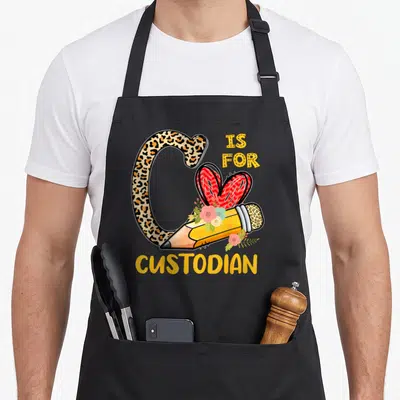 Custodian leopard apron - Leopard print letter C with pencil flowers and red heart reading IS FOR CUSTODIAN — shown on a black cotton canvas apron against a white background