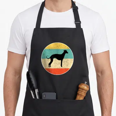 Retro whippet dog apron - Black whippet silhouette on four colored stripes: yellow, teal, beige, red circle — shown on a black cotton canvas apron against a white background