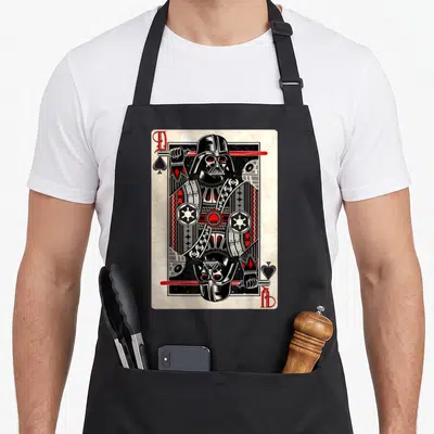 Spade king apron - Darth Vader playing card design in black, red, white, and grey line art — shown on a black cotton canvas apron against a white background