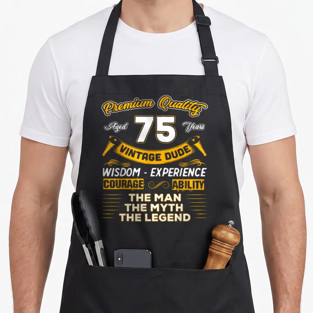 Yrs birthday apron - Yellow and white stacked text reading Aged 75 Years Vintage Dude The Man Myth Legend — shown on a black cotton canvas apron against a white background