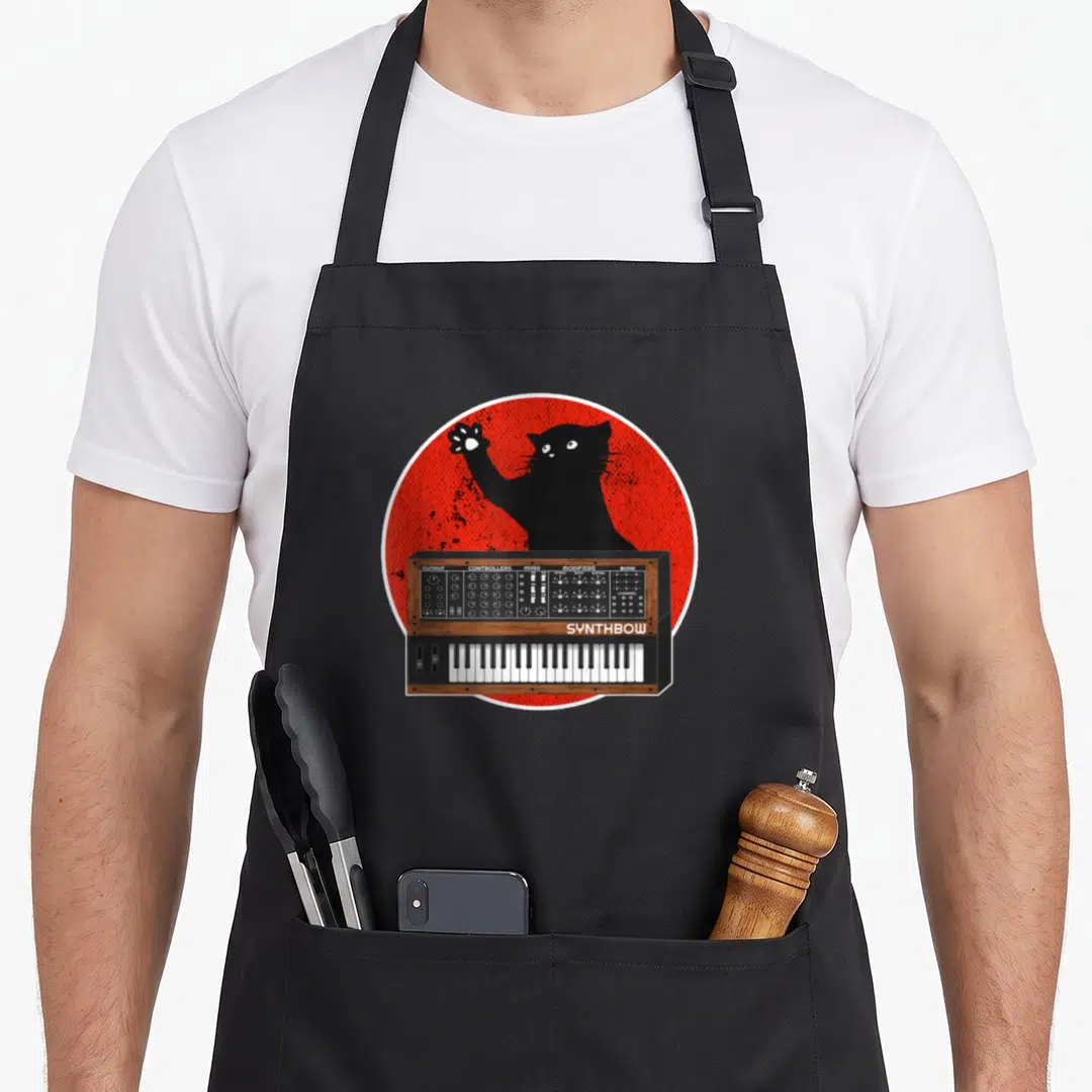 Waveform cat apron - Black cartoon cat behind synth keyboard with red circle background and white text labels — shown on a black cotton canvas apron against a white background