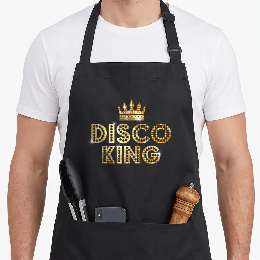 Disco king apron - Gold disco ball patterned crown above stacked DISCO KING text — shown on a black cotton canvas apron against a white background