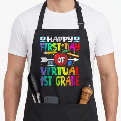 Virtual 1st teacher apron - Stacked colorful text reading Happy First Day of Virtual 1st Grade around a red apple — shown on a black cotton canvas apron against a white background