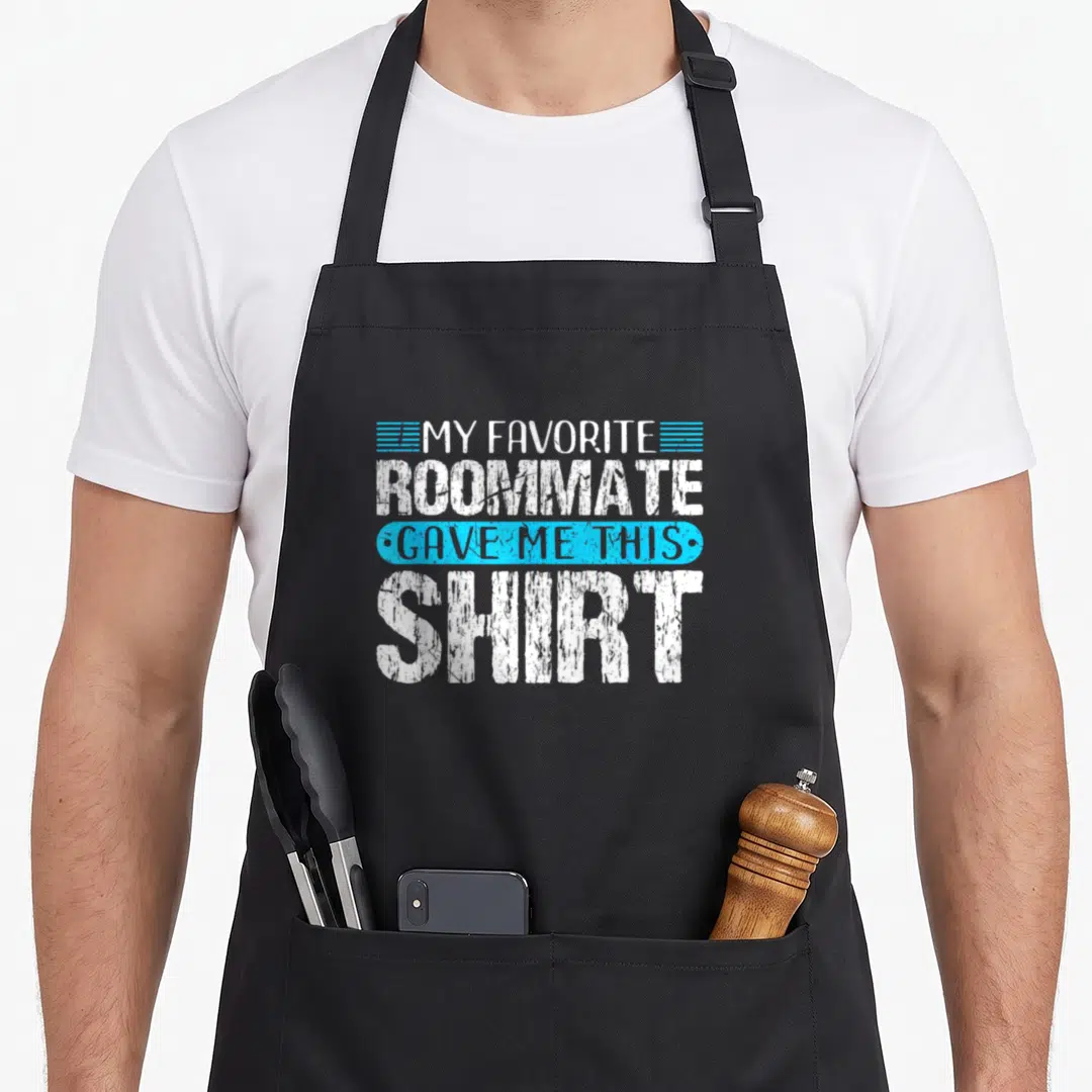 Funny gave roommate apron - White and blue text reading MY FAVORITE ROOMMATE GAVE ME THIS SHIRT stacked on black — shown on a black cotton canvas apron against a white background