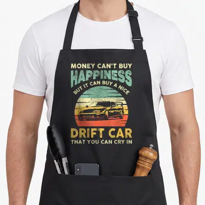 Joke car apron - Retro sunset graphic with drift car silhouette and text about buying a drift car — shown on a black cotton canvas apron against a white background