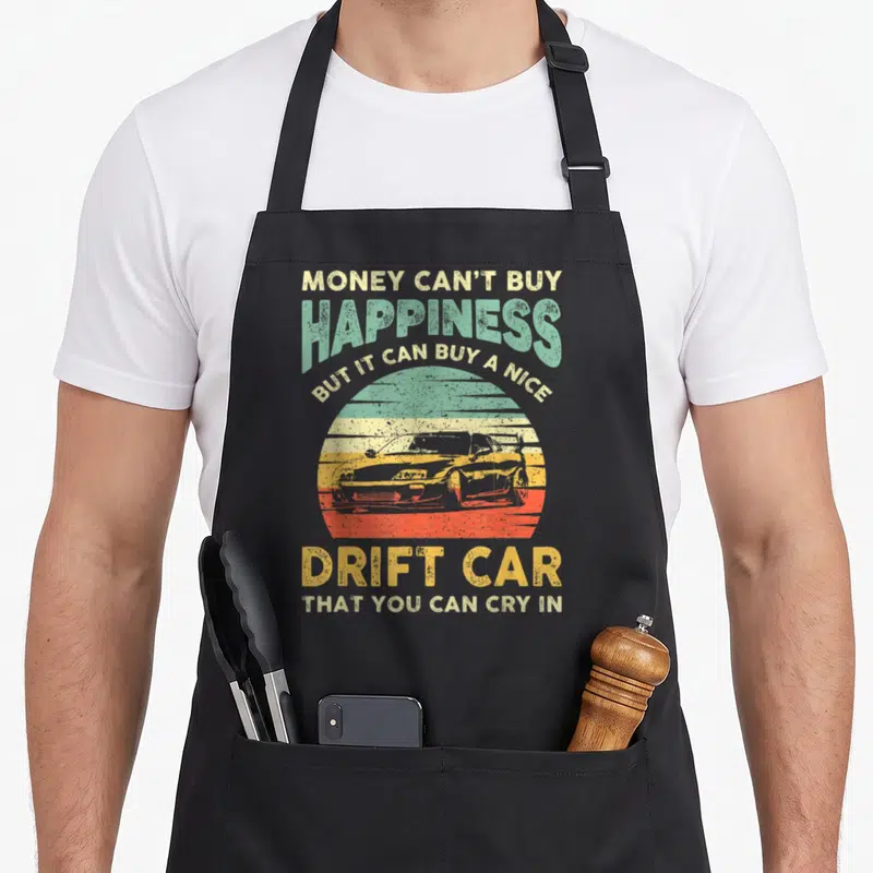 Joke car apron - Retro sunset graphic with drift car silhouette and text about buying a drift car — shown on a black cotton canvas apron against a white background
