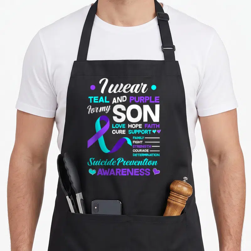 Son suicide prevention apron - I wear TEAL AND PURPLE for my SON text with teal purple ribbon and small hearts — shown on a black cotton canvas apron against a white background