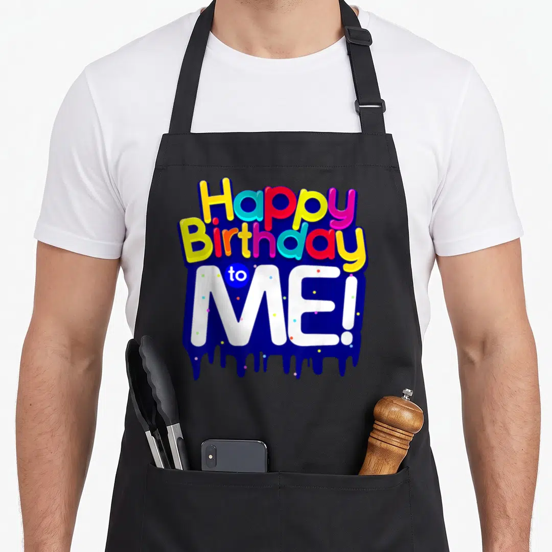 Age born day apron - Stacked colorful text Happy Birthday to ME! over blue dripping shape with scattered dots — shown on a black cotton canvas apron against a white background