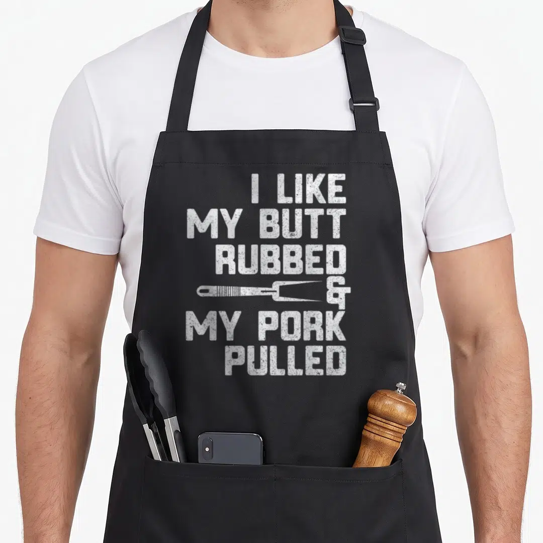 Rubbed pulled addict apron - White stacked text I like my butt rubbed and my pork pulled with meat fork — shown on a black cotton canvas apron against a white background