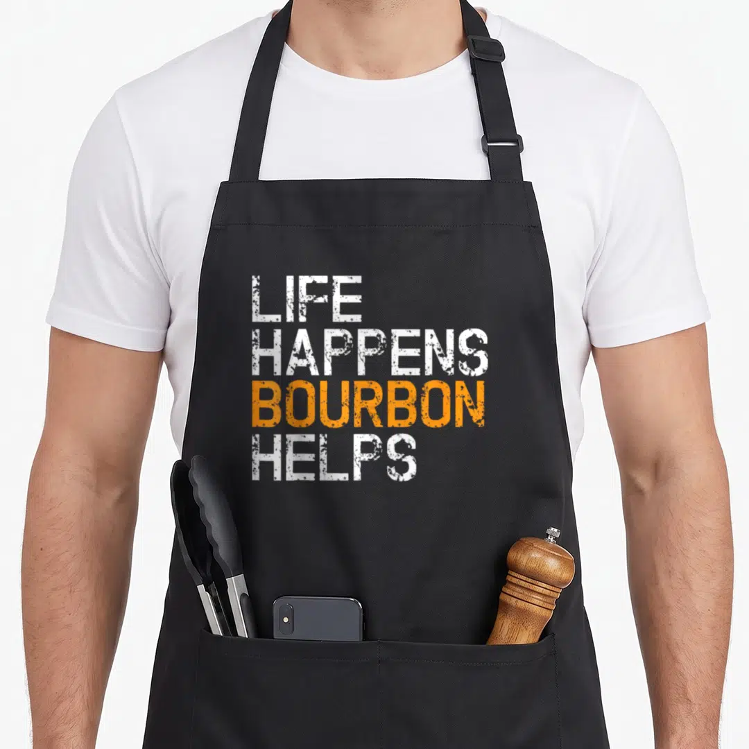 Happen bourbon apron - Stacked LIFE HAPPENS BOURBON HELPS text in white and orange distressed typography — shown on a black cotton canvas apron against a white background