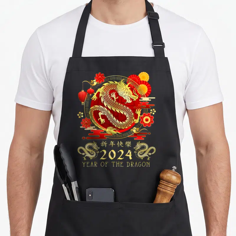 Funny chinese dragon apron - Gold dragon in red circle with 2024 text and smaller dragons below — shown on a black cotton canvas apron against a white background