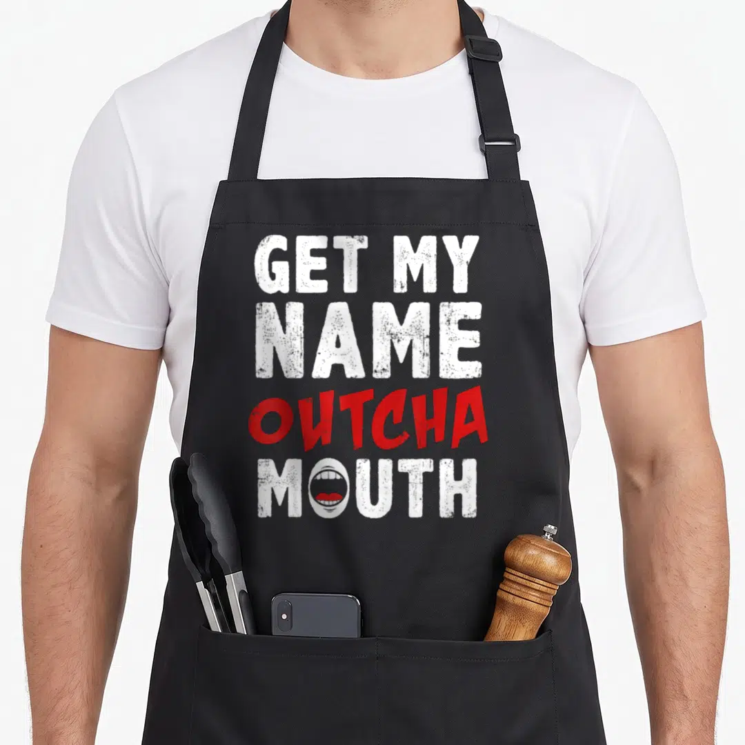Outcha gossip apron - Distressed white and red text GET MY NAME OUTCHA MOUTH with mouth graphic in O — shown on a black cotton canvas apron against a white background