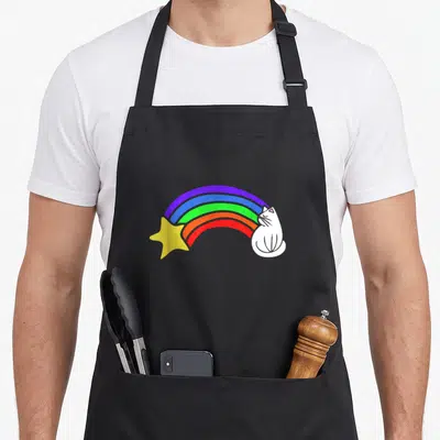 Funny rainbow cat apron - White cartoon cat with rainbow arc connecting to yellow star in purple blue green orange red — shown on a black cotton canvas apron against a white background