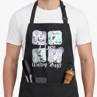 Frozen colorful apron - Four Olaf portraits in white blue purple grid with I Love Warm Hugs script — shown on a black cotton canvas apron against a white background