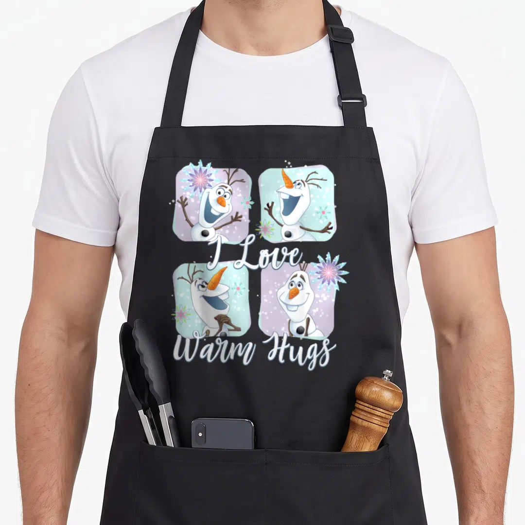Frozen colorful apron - Four Olaf portraits in white blue purple grid with I Love Warm Hugs script — shown on a black cotton canvas apron against a white background