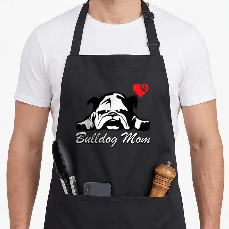 Cute bulldog english aprons - Black and white bulldog head with red heart paw print and Bulldog Mom script text — shown on a black cotton canvas apron against a white background