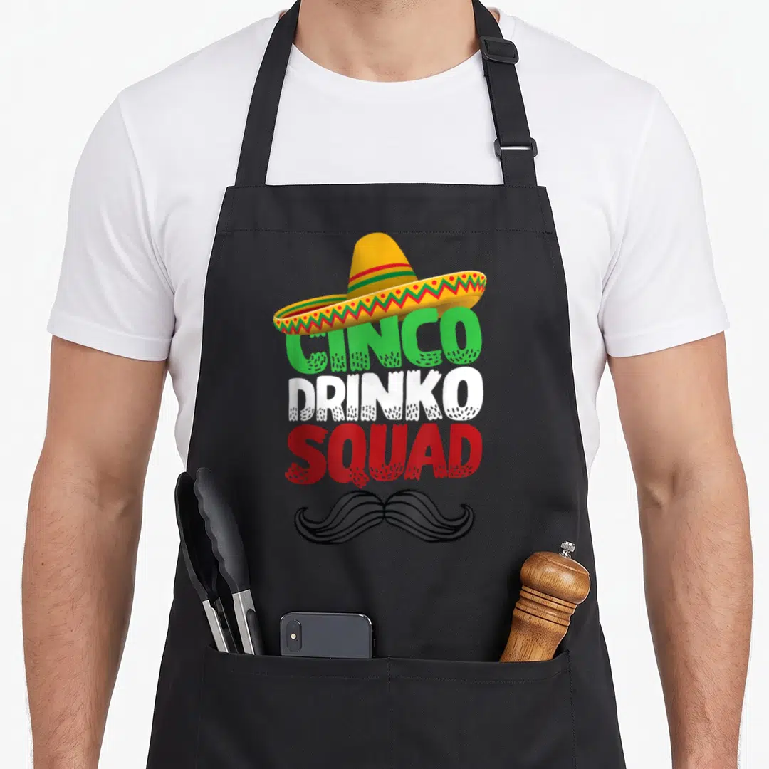 Drinko mexican apron - Cartoon sombrero above green white and red text reading Cinco Drinko Squad with a black mustache — shown on a black cotton canvas apron against a white background
