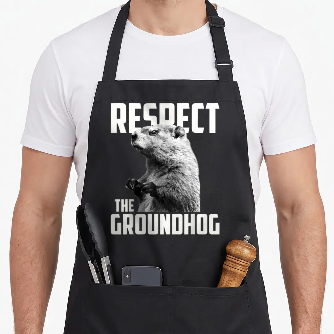 Respect ground groundhog apron - Photo-style groundhog standing between white text reading Respect The Groundhog — shown on a black cotton canvas apron against a white background