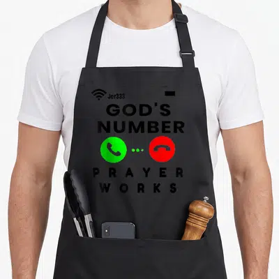 Writing prayer apron - Stacked text GODS NUMBER PRAYER WORKS with green accept and red decline phone buttons separated — shown on a black cotton canvas apron against a white background
