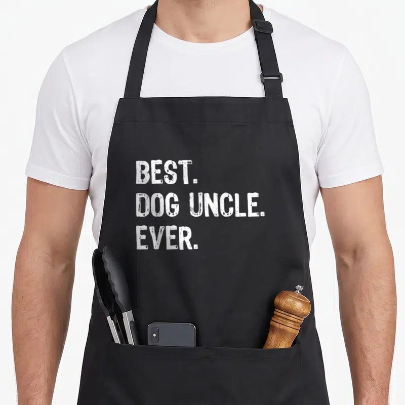 Uncle dog apron - White stacked text reading BEST DOG UNCLE EVER in distressed block font — shown on a black cotton canvas apron against a white background