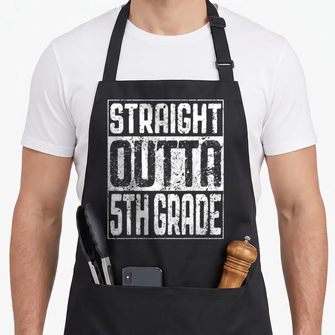 Straight miss grade apron - Distressed white text reading STRAIGHT OUTTA 5TH GRADE stacked vertically — shown on a black cotton canvas apron against a white background