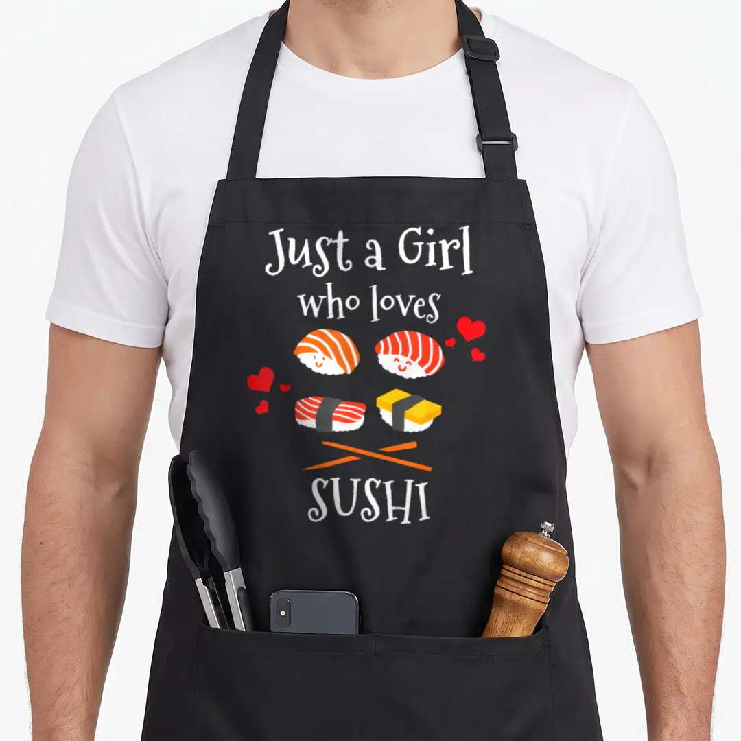 Cute sushi apron - Four cartoon sushi pieces with hearts and crossed chopsticks under Just a Girl who loves SUSHI text — shown on a black cotton canvas apron against a white background