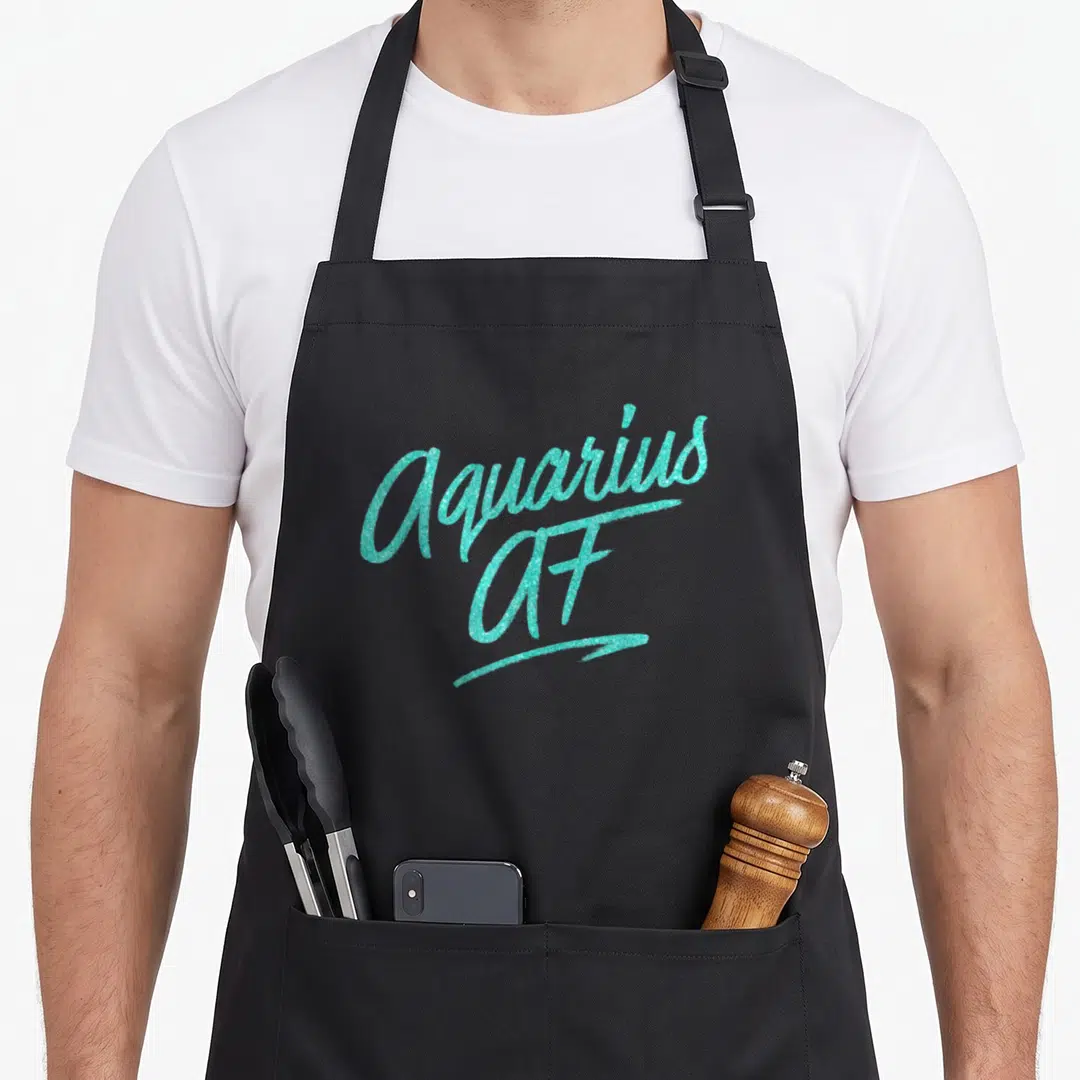 Aquarius star zodiac aprons - Turquoise glitter script reading Aquarius AF stacked on two lines — shown on a black cotton canvas apron against a white background