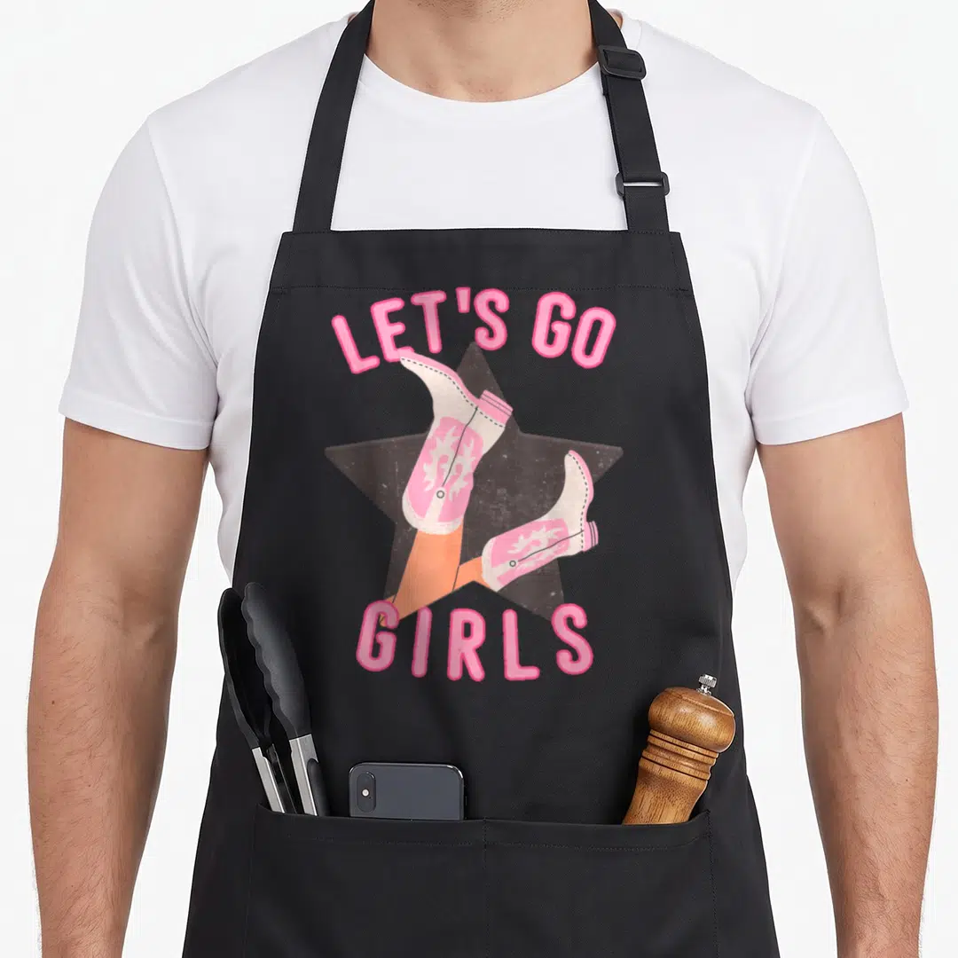 Bridal western apron - Pink cowboy boots kicking up over dark star with LET'S GO GIRLS text — shown on a black cotton canvas apron against a white background