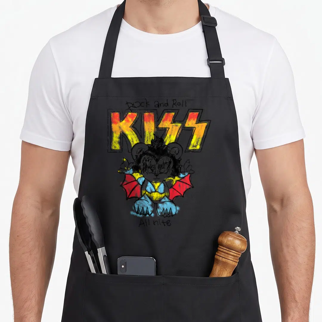 Kiss line apron - Cartoon bear with bat wings under Rock and Roll KISS All nite text in yellow orange red blue black — shown on a black cotton canvas apron against a white background