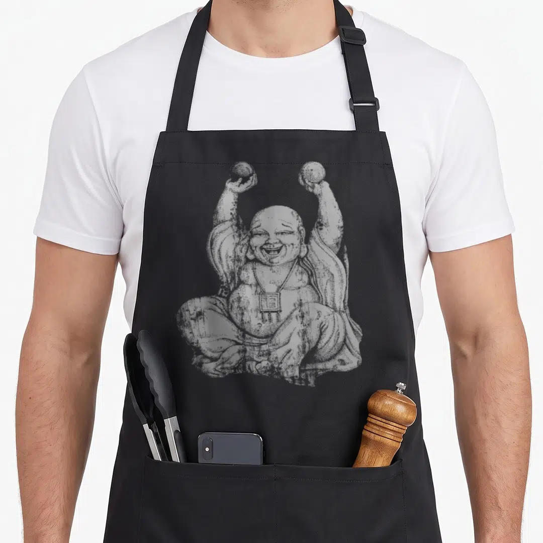 Laughing yoga apron - Grey line-art Laughing Buddha holding two beads aloft with a square pendant — shown on a black cotton canvas apron against a white background