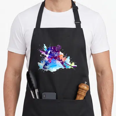 Ice paint apron - Hockey player silhouette with purple blue cyan orange watercolor splashes — shown on a black cotton canvas apron against a white background