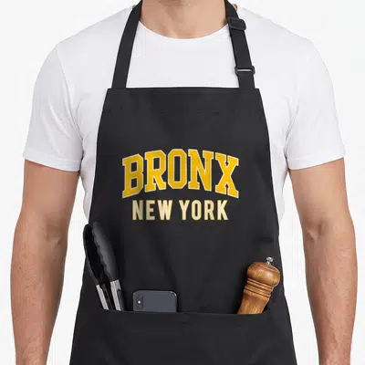 Retro bronx new york apron - Arched yellow BRONX text above straight white NEW YORK text — shown on a black cotton canvas apron against a white background