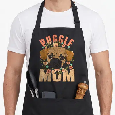 Animal mother's day aprons - Cartoon Puggle dog head with peach flowers and PUGGLE MUM text — shown on a black cotton canvas apron against a white background